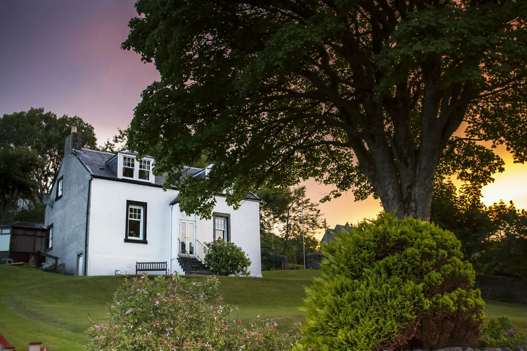 Maison blanche entourée d'arbres au coucher du soleil